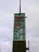 Glasaufzugsturm mit roter Aufschrift 