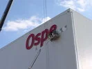 Arbeiter auf Hebebühne montiert großes rotes Schild mit Schriftzug 