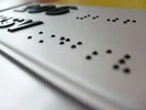 Nahaufnahme von erhabenen Brailleschriftpunkten auf einer weißen Oberfläche